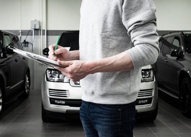 service de réparation de voiture concept d'entretien mécanicien écrivant sur le bloc-notes à l'atelier technicien d'entrepôt faisant la liste de contrôle pour la machine de réparation une voiture dans le détail