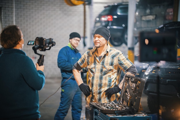 Service de réparation de voitures dans les coulisses du tournage d'un mécanicien brutal debout devant une caméra