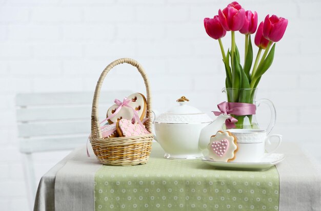 Service à thé avec des fleurs sur table sur fond clair