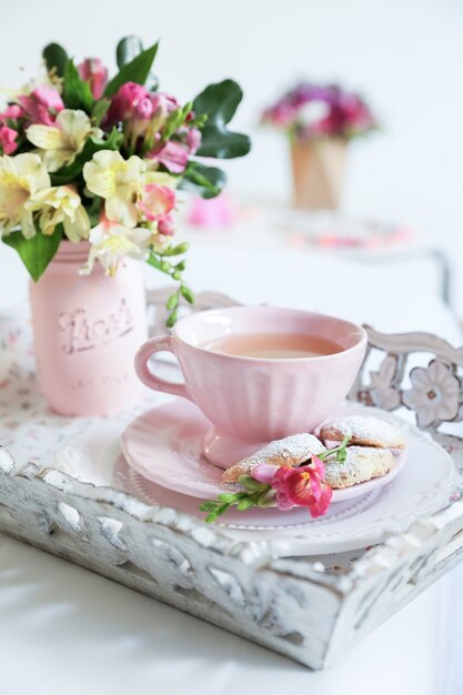 Service à thé rose avec des fleurs sur une table