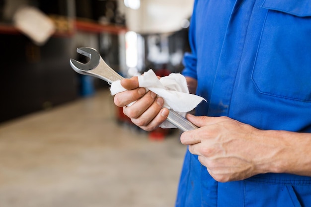 service de voiture, réparation, entretien et concept de personnes - mécanicien automobile ou forgeron avec clé à l'atelier