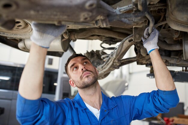 service de voiture, réparation, entretien et concept de personnes - mécanicien automobile ou forgeron travaillant à l'atelier