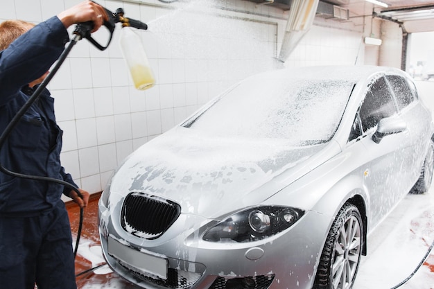 Serviceman in carwash lavage voiture avec flexible