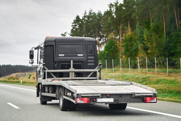 Photo services de remorquage et de récupération fiables 247 assistance en cas de panne de véhicule et d'accident assistance routière d'urgence sur la route vue latérale du remorqueur à plat