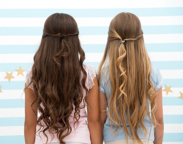 Services de salon de coiffure. deux petites filles aux cheveux longs chez le coiffeur. petites filles aux longs cheveux bouclés. cheveux longs et sains. masque à la kératine