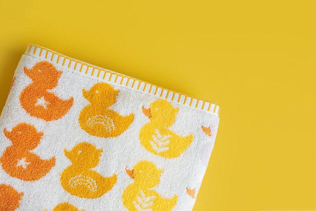 Serviette bébé avec des canards mignons sur fond jaune.