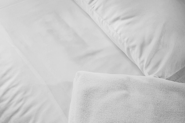 Serviette blanche sur un matelas blanc, lumière douce le matin. Contexte