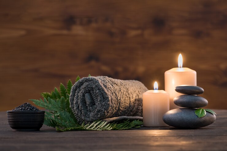 Photo serviette brune avec bougies et pierre chaude noire sur fond de bois.