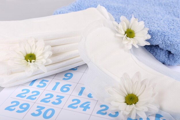 Serviette de calendrier de serviettes hygiéniques et fleurs blanches sur fond clair