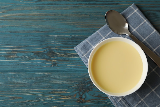 Serviette, cuillère et bol avec du lait concentré sur une surface en bois