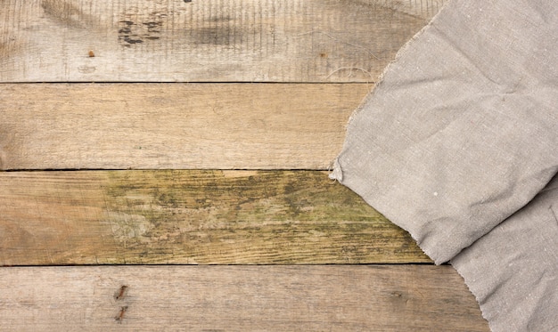 Serviette de cuisine en lin gris sur une table faite de vieilles planches de bois, vue de dessus, espace pour copie