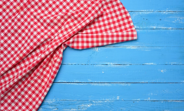 Serviette de cuisine pliée en coton rouge et blanc sur fond bleu en bois, vue de dessus, espace pour copie