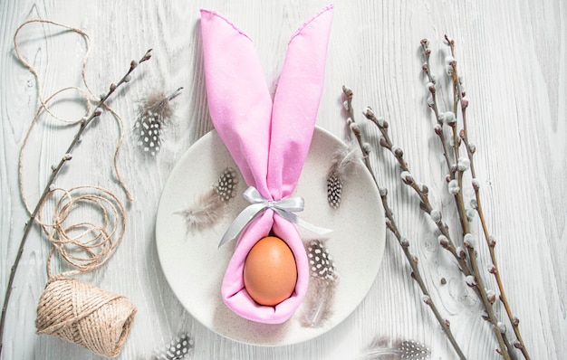 Serviette en forme de lapin de Pâques avec un œuf à l'intérieur avec décoration de Pâques sur fond clair.