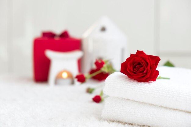 Photo des serviettes blanches fraîches avec une rose rouge et des bougies sur fond blanc