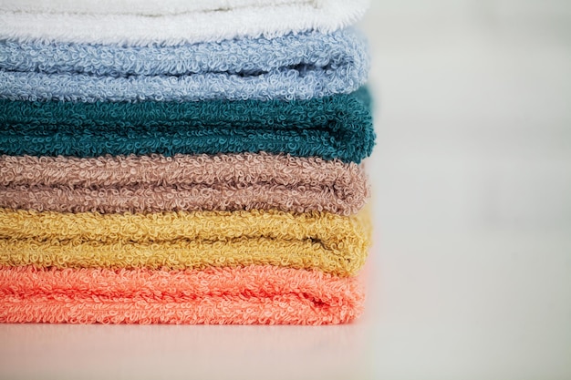 Serviettes en coton coloré dans la salle de bain sur une table en bois blanche.