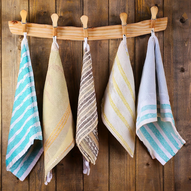 Des serviettes de cuisine pliées colorées accrochées à une corde sur un fond en bois