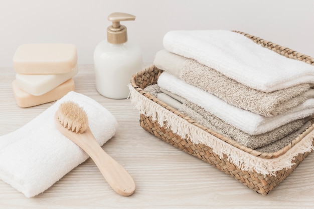 Photo serviettes empilées; brosse; savon et bouteille cosmétique sur une surface en bois