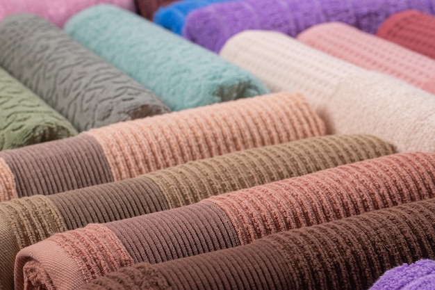 serviettes éponge multicolores enroulées et disposées en rangée sur la table