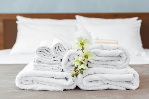 Serviettes et fleurs sur le lit dans la chambre d&#39;hôtel