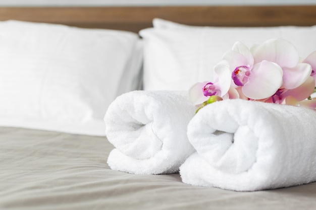 Serviettes et fleurs sur le lit dans la chambre d&#39;hôtel