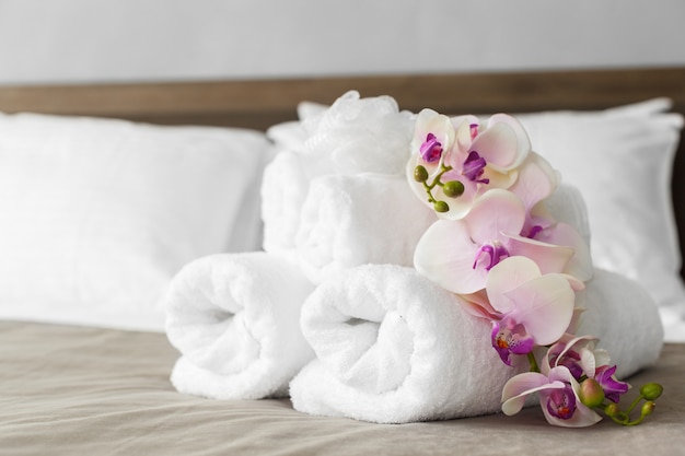 Serviettes et fleurs sur lit dans la chambre d'hôtel