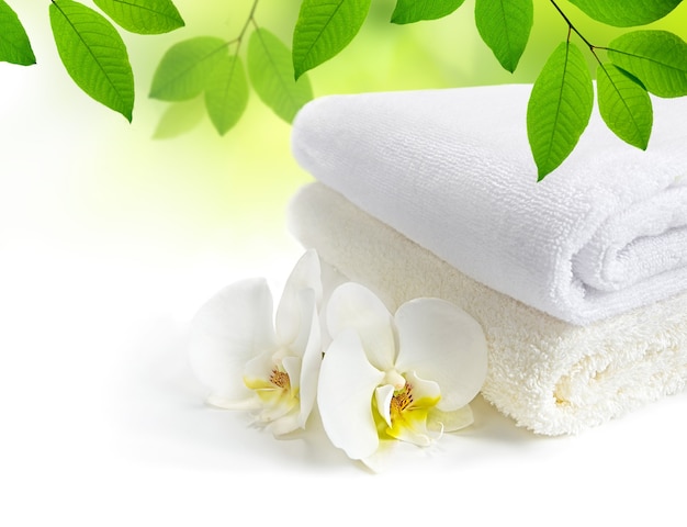 Serviettes de spa avec des fleurs d'orchidées blanches et des feuilles vertes sur fond blanc