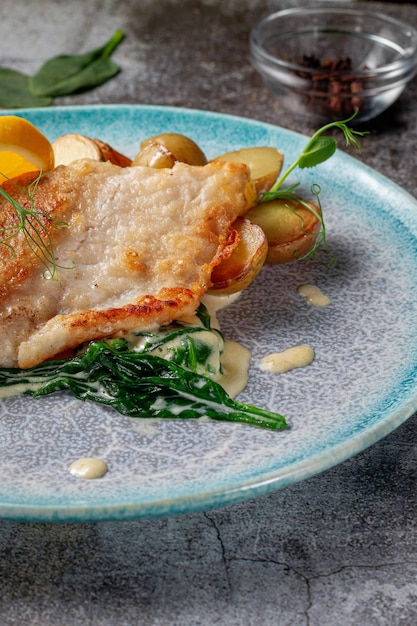 Servir un plat d'un menu de restaurant. Steak de truite au four avec citron, salade et verts d'aneth et de persil sur une assiette contre une table en pierre grise