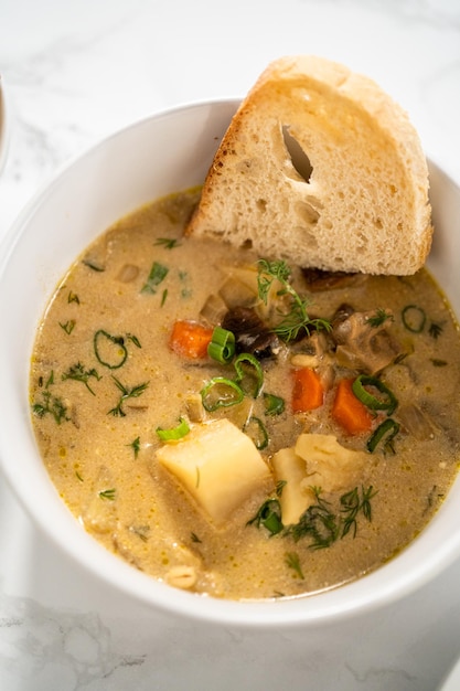 Servir une soupe crémeuse aux champignons sauvages faite de champignons sauvages déshydratés dans des bols blancs avec du pain au levain