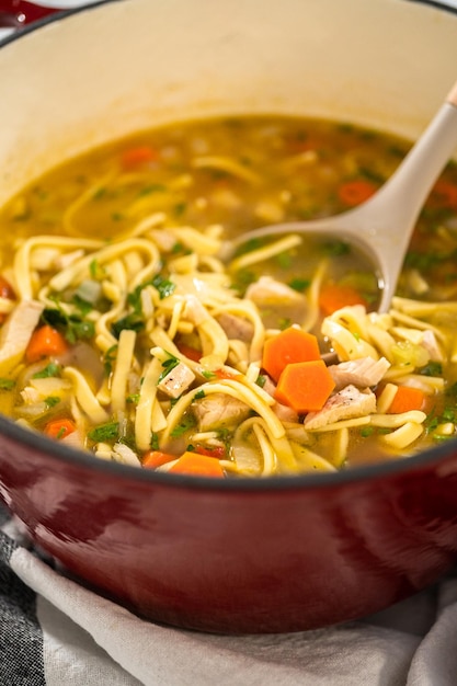 Servir une soupe de nouilles au poulet avec des nouilles kluski dans des bols à soupe en céramique blanche