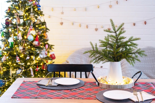 Servir une table festive avec des assiettes, des fourchettes, des couteaux, des serviettes, des verres en gros plan dans l'intérieur moderne