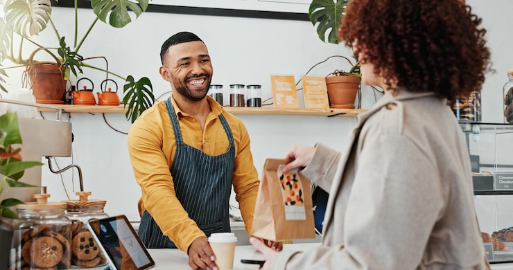 Photo serviteur sac et client dans le café pour l'hospitalité déjeuner et paiement en ligne avec café et paquet femme serveur et sourire dans le restaurant à vendre échange et petit déjeuner avec un service professionnel