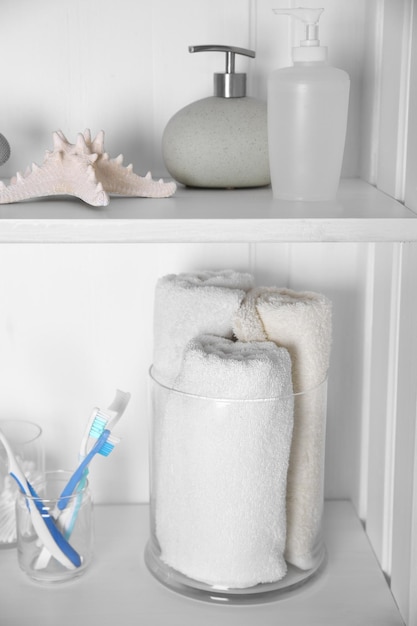 Photo set de salle de bain avec des serviettes, des brosses à dents d'étoile de mer et des distributeurs sur une étagère légère