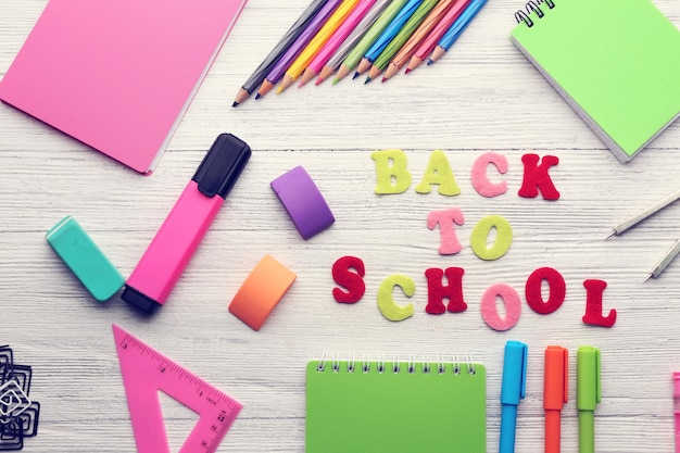 Set scolaire avec des cahiers d'inscription de retour à l'école sur un fond en bois clair