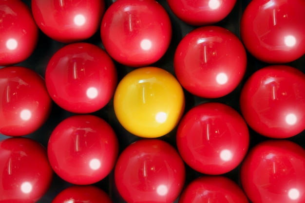 Seul ballon de billard jaune entre plusieurs boules rouges