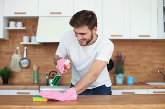 Seul bel homme nettoyant la cuisine à la maison.