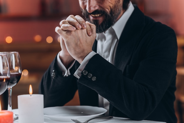 Seul homme barbu en costume est assis seul à une table dans un restaurant gros plan