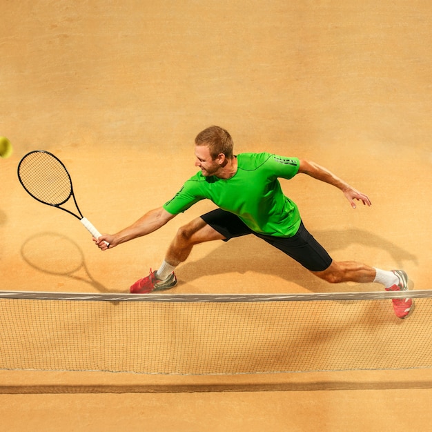 Le seul joueur de saut, homme en forme de race blanche, jouant au tennis sur le court de terre