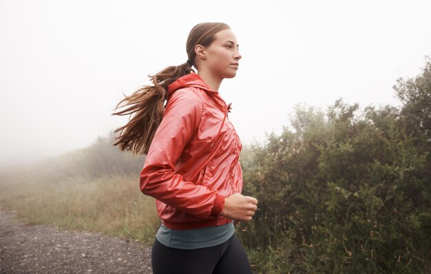 La seule façon de courir Photo d'une jeune femme jogger dans une route de campagne brumeuse le matin