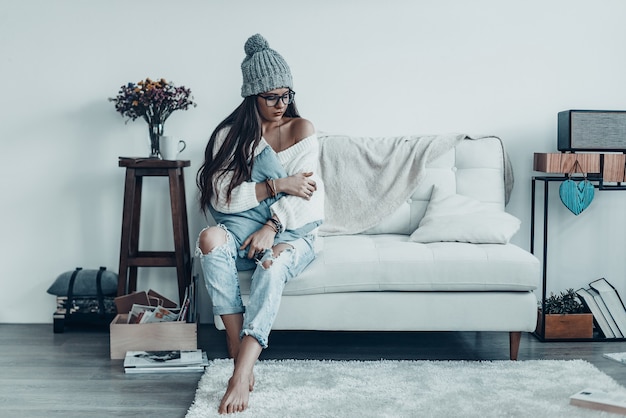 Seule avec ses pensées. Belle jeune femme en tenue décontractée et bonnet en tricot embrassant l'oreiller