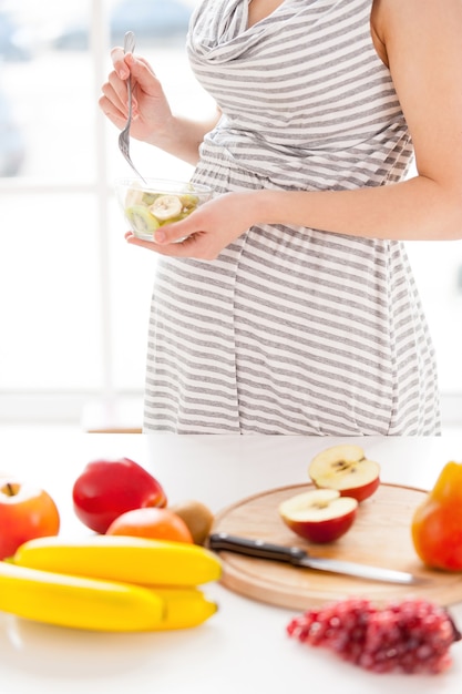 Seulement des aliments sains pour mon bébé. Image recadrée d'une femme enceinte mangeant une salade de fruits