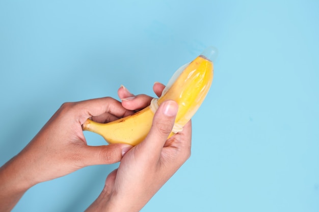 Sexe éducatif avec banane à la main isolé sur fond bleu