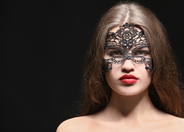 Sexy belle femme avec masque de carnaval sur fond noir