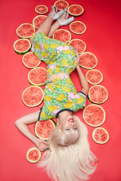 Sexy belle jeune femme allongée sur le sol posant pour une séance photo entourée de pastèque