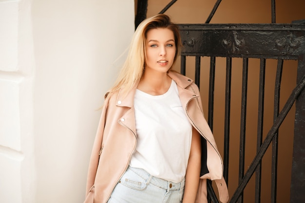 Sexy belle jeune femme dans une veste rose avec un t-shirt blanc et un short en jean dans la rue