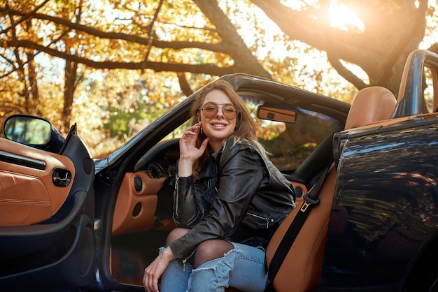 Sexy jeune femme en jeans souriant dans un cabriolet