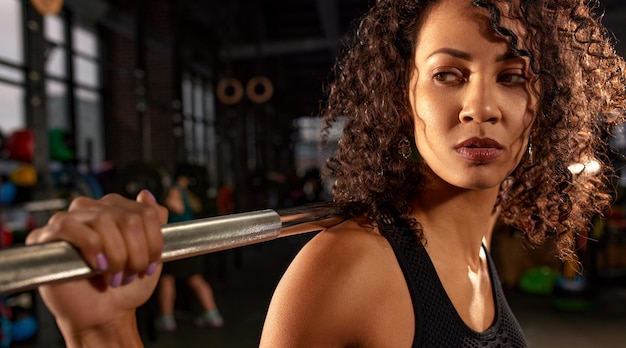 Photo sexy magnifique femme afro-américaine s'entraînant avec des haltères au gymnase