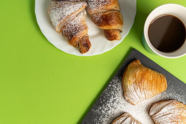 Sfogliatella et croissant au chocolat avec des tasses à café sur fond vert clair