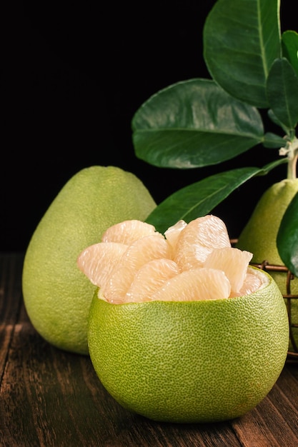 Shaddock de pamplemousse pomelo frais pelé avec des feuilles vertes sur une table en bois foncé