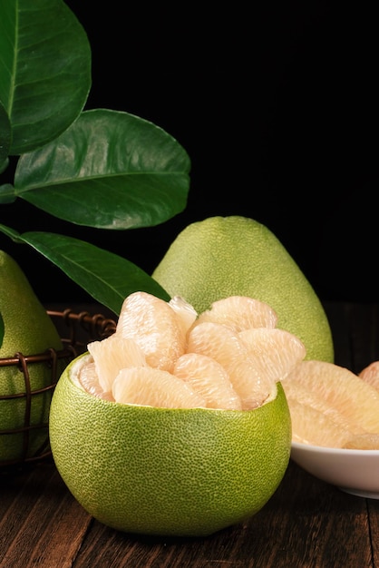 Shaddock de pamplemousse pomelo frais pelé avec des feuilles vertes sur une table en bois foncé