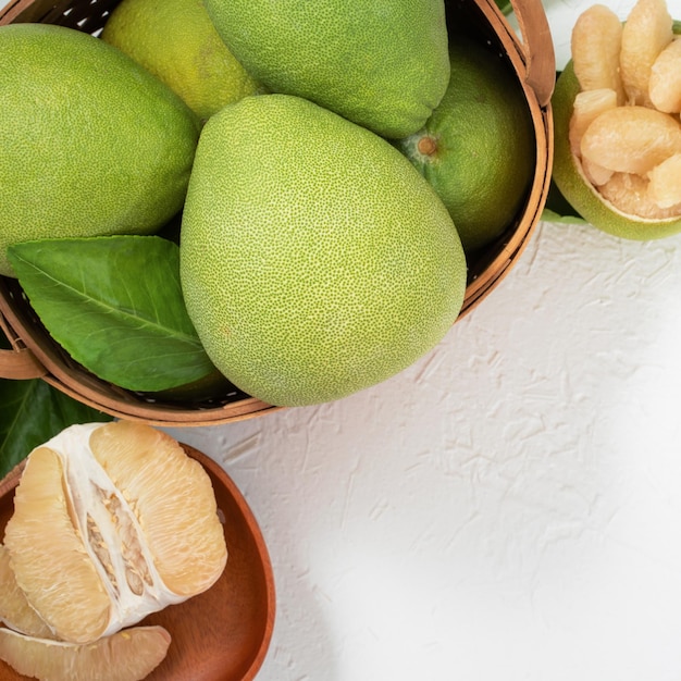 Shaddock de pamplemousse pomelo pomelo frais sur fond de ciment blanc dans un panier en bambou fruits de saison d'automne vue de dessus plan de table plat